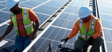 Two men working on a roof installing solar panels